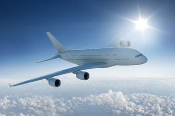 Big airplane flying above the clouds with the sun in blue sky