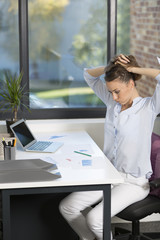 Young woman in an office holding her head in her hands at her desk because of a mistake or error