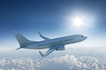 Airliner flying above the clouds with the sun in blue sky