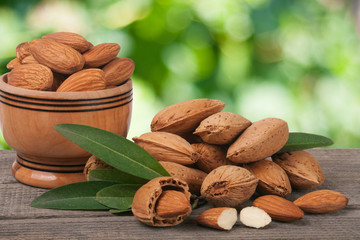 almonds in a bowl on the old wooden board with blurred garden background
