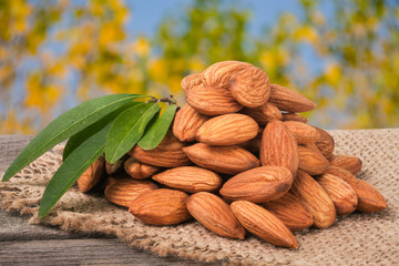 heap of peeled almonds with leaf on a wooden table blurred garden background