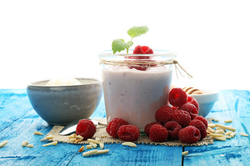 Beautiful appetizer pink raspberries fruit smoothie or milk shake in glass jar with berries background, top view. Yogurt cocktail. Close up. Natural detox. Liquid ice cream. 
