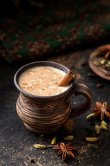 Masala pulled tea chai latte hot Indian sweet milk spiced drink, cinnamon stick, ginger, fresh spices and herbs blend, organic infusion healthy wellness beverage teatime ceremony in rustic clay cup