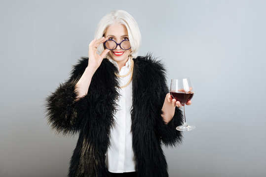 Smiling senior pretty woman holding wineglass.