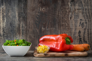 Kale salad in bowl with carrot, pepper and sweet corn on wooden background   © chandlervid85
