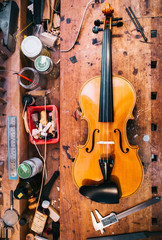 Naklejka premium Geige auf Werkbank/Violine liegt auf einer Werkbank