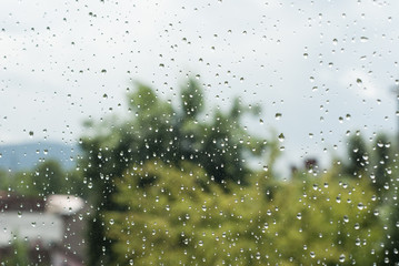 raindrops od window glass with trees and city as background