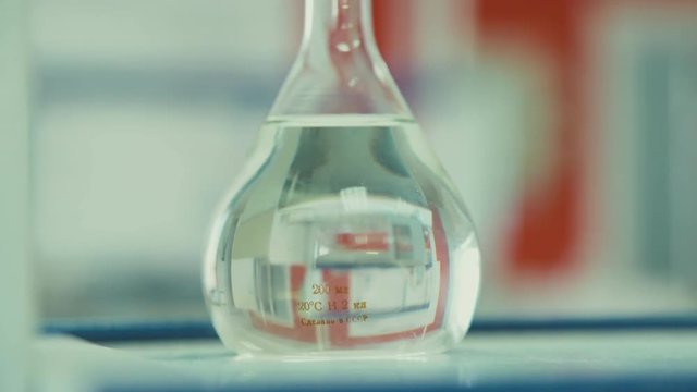 Chemical flask with a clear liquid on the table. Chemical Laboratory. Preparations for the chemical experiment. The inscription on the flask: Made in the USSR