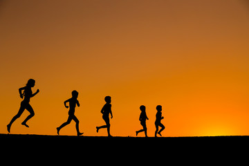silhouette of five running kids against sunset