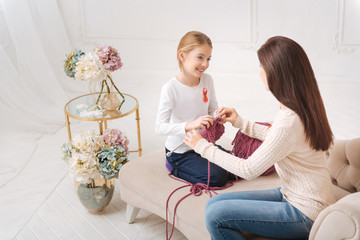 Happy nice mother teaching her daughter to knit
