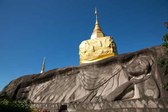 golden pagoda with buddha carved stone at  wat tham pha daen in
