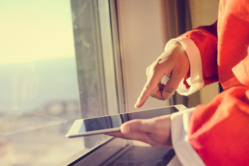 Santa Claus working at desk and using apps on a touch screen tablet