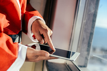 Santa Claus working at desk and using apps on a touch screen tablet