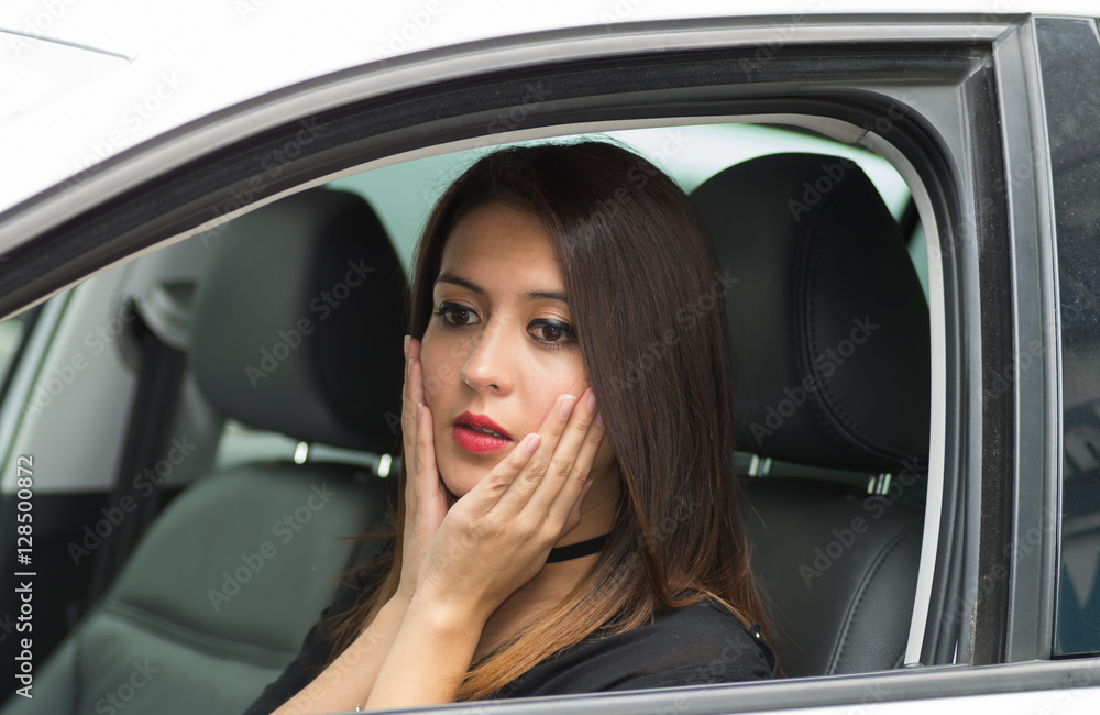 Wall mural closeup young woman sitting in car interacting slightly shocked, as seen from outside drivers window