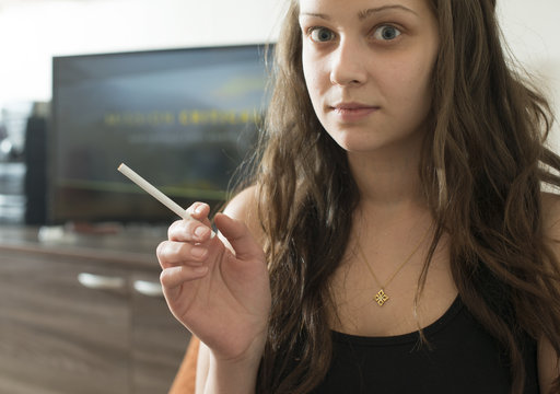 Girl smoke cigarette in the house. Close up cigarette.