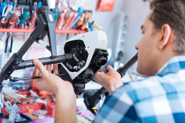 Fototapeta premium Young handsome man holding drone details in workroom