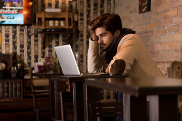 Fototapeta premium Young man sitting in a cafe and working on his laptop.