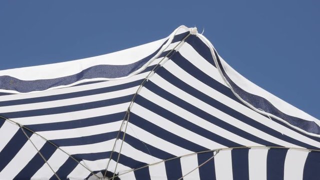 Colorful umbrella fabric made for protection from the sun slow motion 1080p FullHD footage - Beach striped blue parasol against clear sky moving on wind slow-mo 1920X1080 HD video 