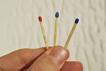 Male hand holding three safety matches, each with a different color of its top as a symbol of...