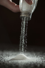 Obraz na płótnie Canvas Adding salt. Backlight to salt from salt shaker.