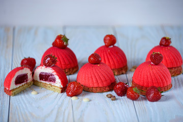 bright red mousse cake with strawberry decoration on a blue wooden background
