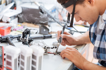 Delighted man soldering drone details attentively