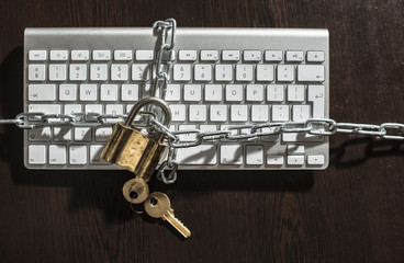 Keys, padlock and keyboard. Shackled keyboard.