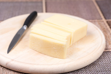 Sliced yellow pizza cheese on the wooden cutting board