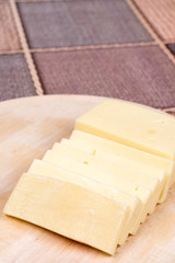 Sliced yellow pizza cheese on the wooden cutting board