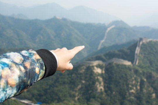 Female hand pointing the Great Wall of China