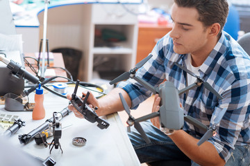 Young man putting together drone propeller and other details