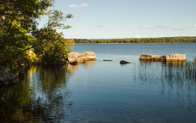 Nature background river Bay with hanging trees and stone boulders in the water