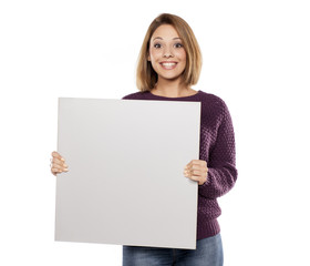 Fototapeta premium young beautiful woman in a purple sweater and jeans, holding a blank board for advertising