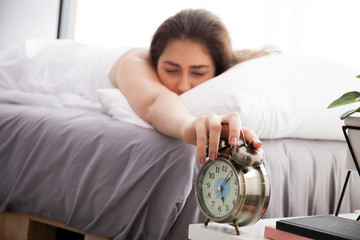 Woman reaching out hands and trying to turn off alarm in the mor
