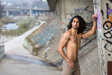 Muscular mediterranean man with naked torso in urban surrounding