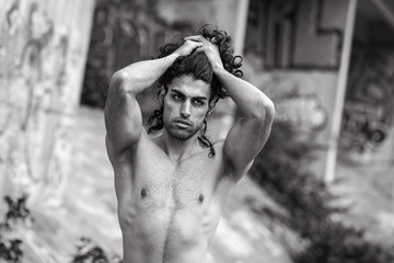 Muscular mediterranean man with naked torso in urban surrounding