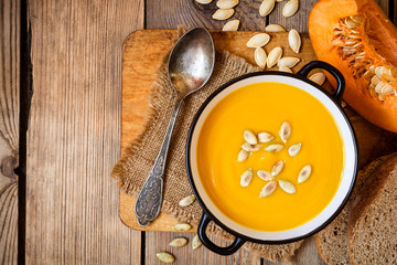 Bowl of pumpkin soup on rustic wooden background