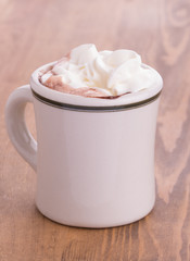 Hot chocolate with cream topping in an antique cup on rustic woden table