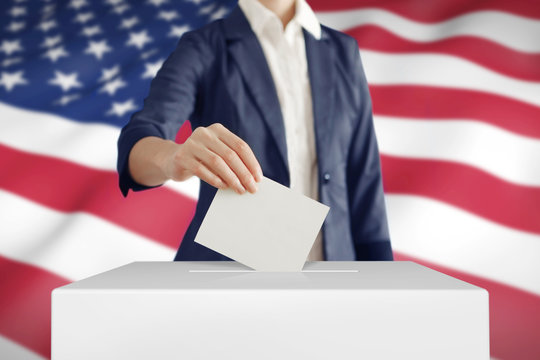 Voting. Woman Putting A Ballot Into A Voting Box With USA Flag On Background.