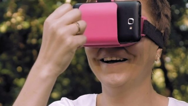 Young woman explores virtual reality using VR glasses. Augmented reality quickly comes into human everyday life. VR helmet and glasses are the most popular devices for playing games and enjoying AR.