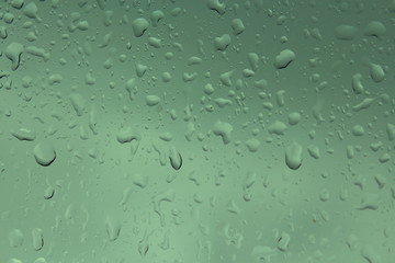 Water drops against green background, wet glass surface car.