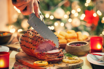 Young woman carving glazed holiday ham - 128515828