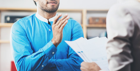 Obraz premium Closeup photo of two coworkers making a great business discussion in modern office.Successful confident hispanic businessman talking with young woman. Horizontal wide, blurred background.