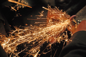 Blacksmith grinding detail at his workshop.  Image full of sparkles