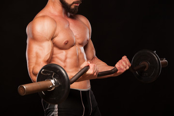 Muscular male athlete is training by lifting the barbell
