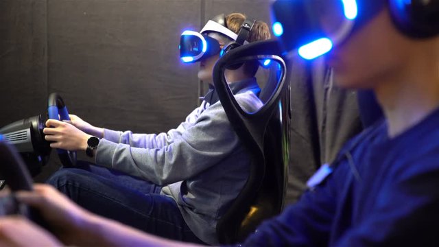 VR games. Teens use virtual reality helmets, racing simulator.