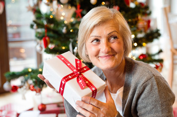 Obraz na płótnie Canvas Beautiful senior woman in front of Christmas tree with present
