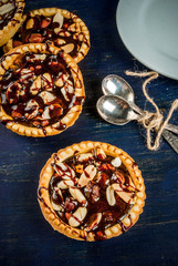 Fototapeta premium Mini tarts with nuts and caramel on a rustic background, top view, copy space