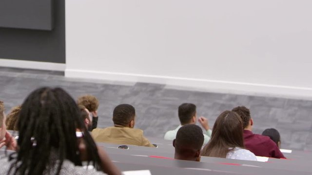 Teacher at lectern in lecture theatre, back row student POV, shot on R3D