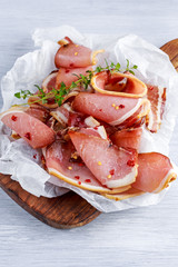 Raw beer bacon slices on crumpled paper which herbs